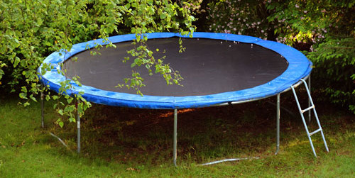 Black and blue trampoline in yard. Trampoline Removal Services in Salem OR by Mike & Dad's Hauling